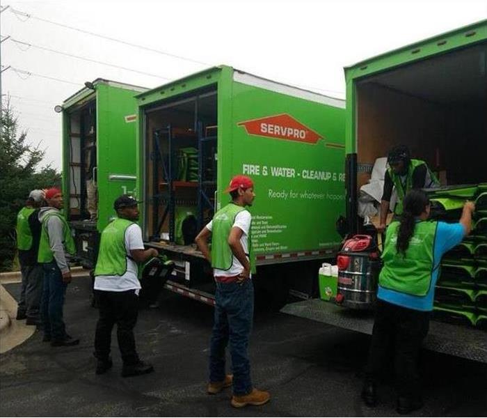 green SERVPRO trucks with 6 people unloading equipment
