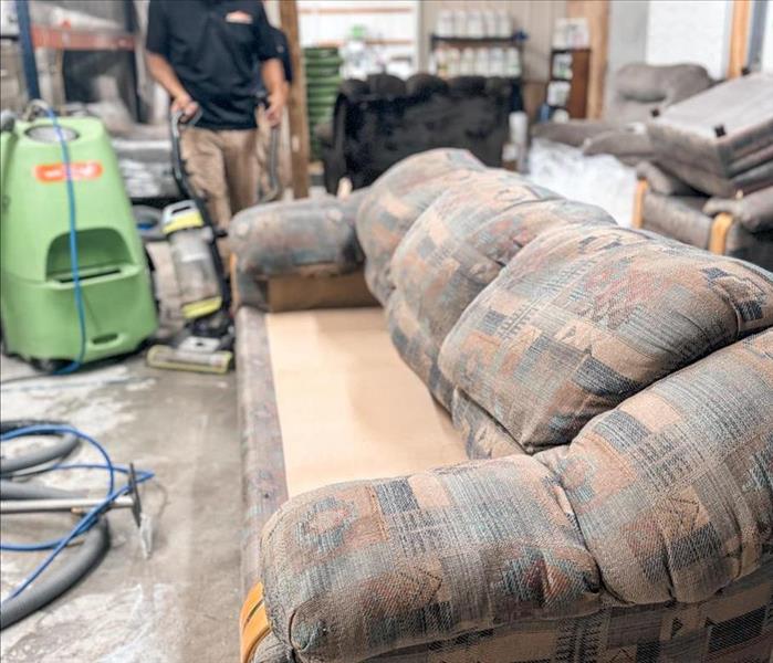 SERVPRO technician cleaning a couch with professional equipment.