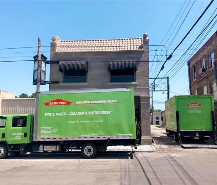 SERVPRO vehicles parked outside a commercial building downtown, ready to begin restoration work.